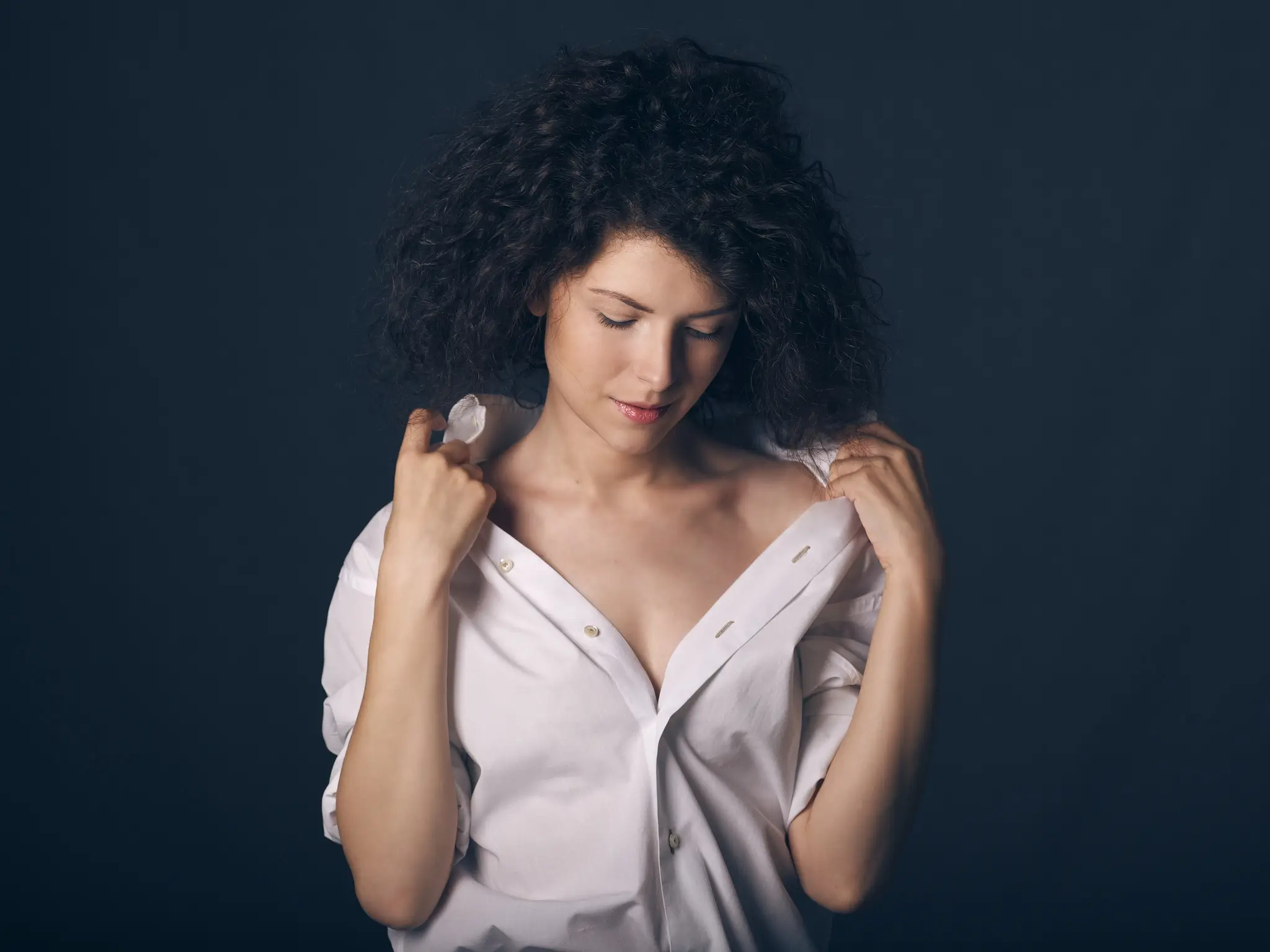 Studio portrait of brunette model with white shirt on blue background