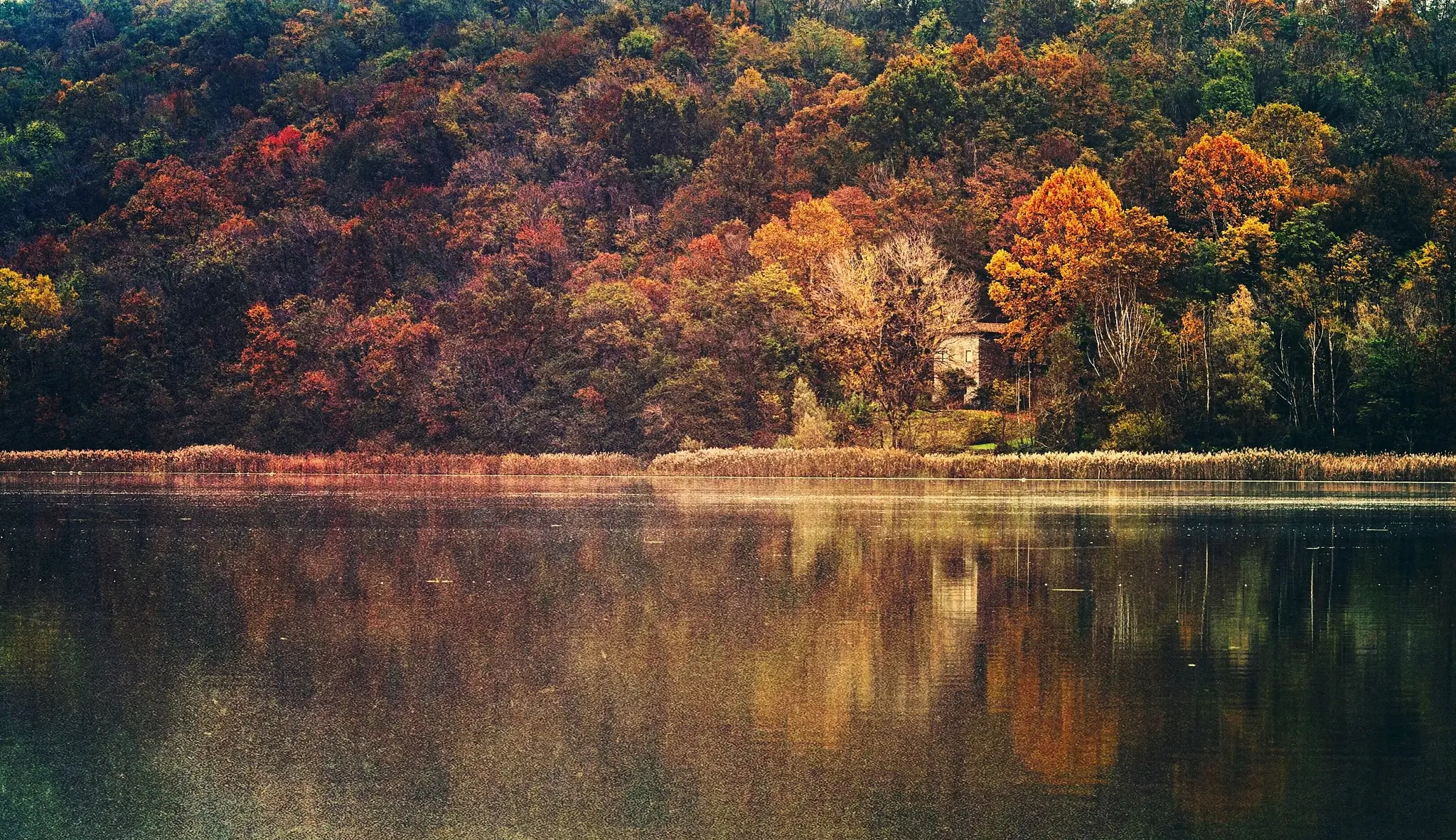Fall landscape - An old house by the lake surrounded by the incredible colors of a forest at fall