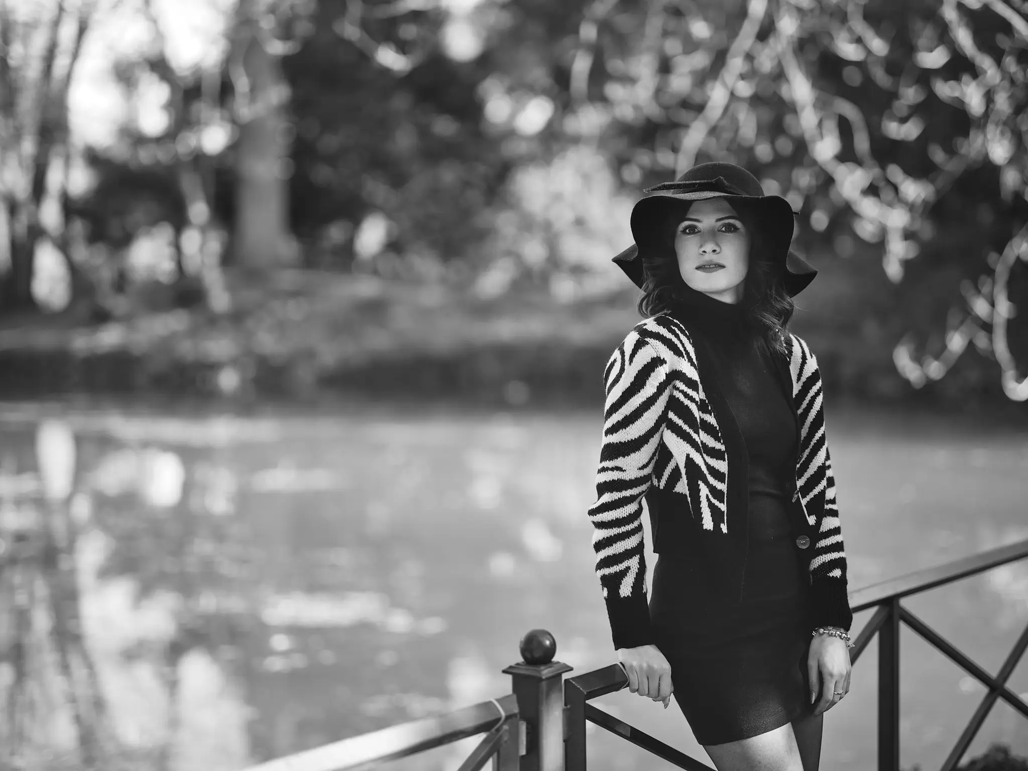 Black and white outdoors portrait of brunette model leaning on a fence