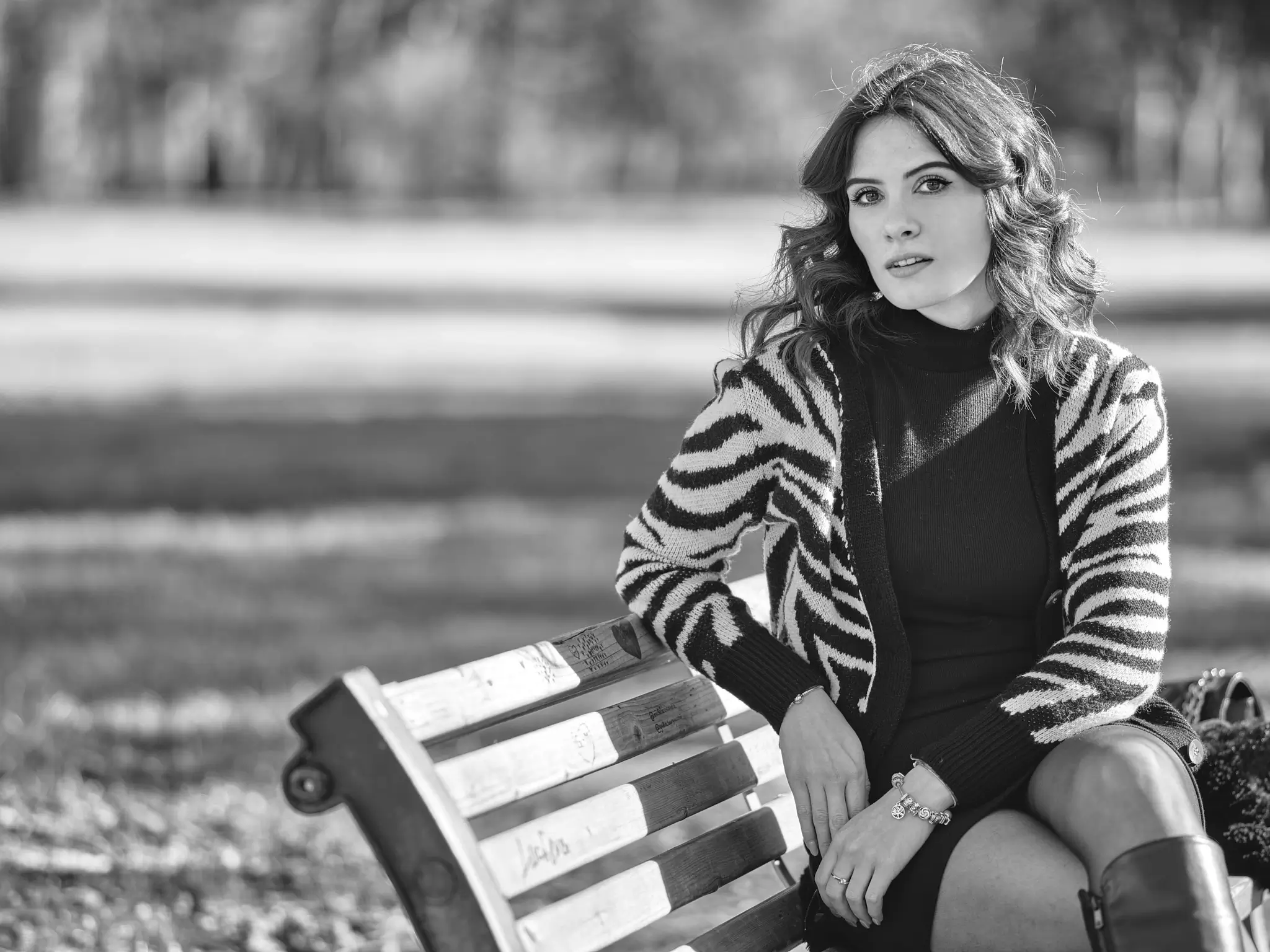 Black and white outdoors portrait of brunette model sitting on a bench